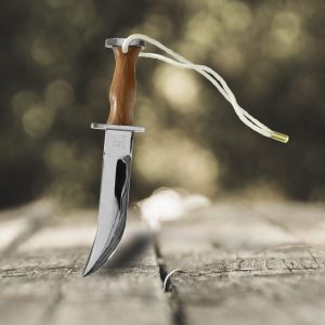 Corvo atacameño cromado con empuñadura de madera natural sobre fondo rústico.